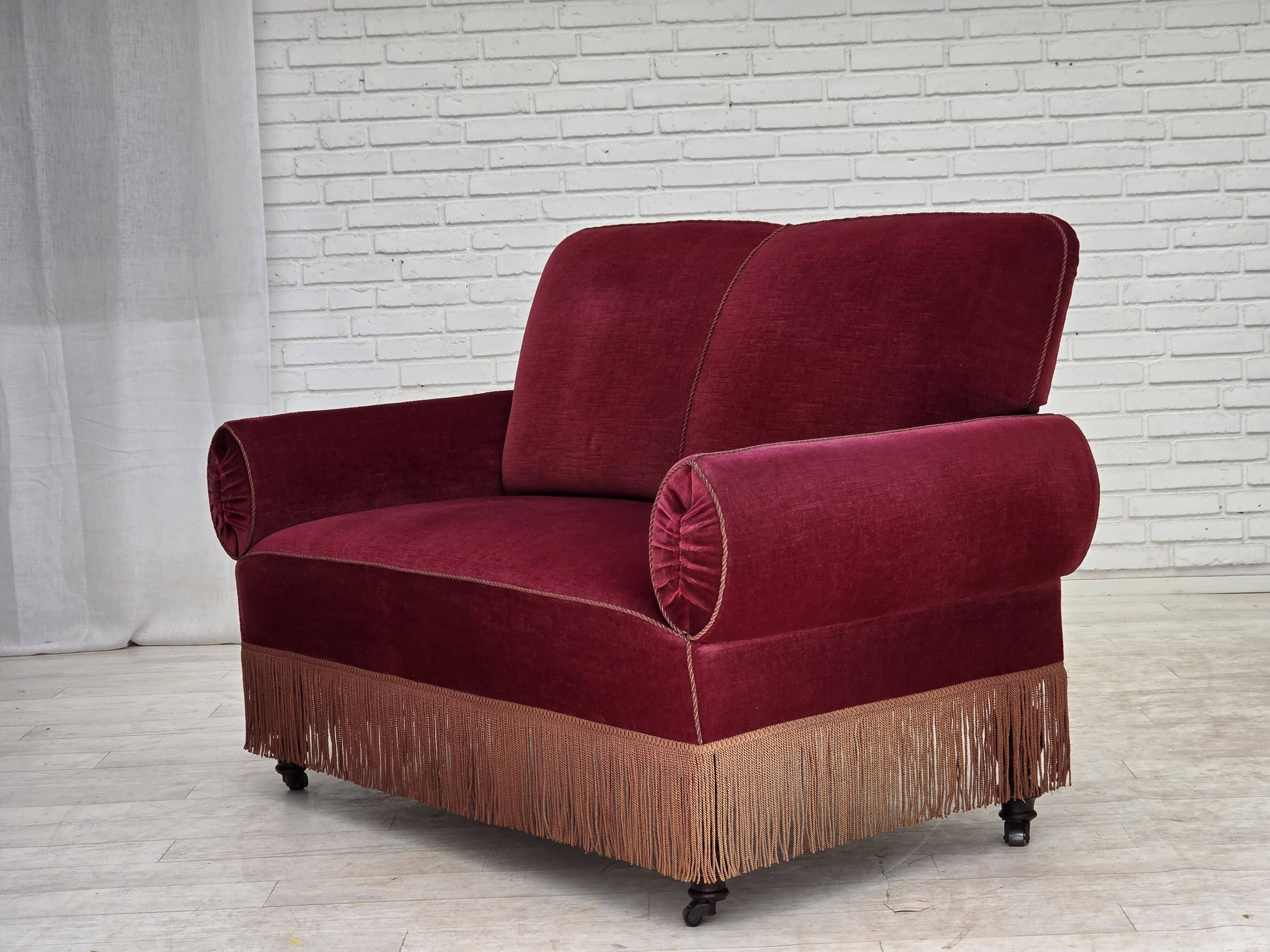 Canapé danois 2 places des années 1950, en velours rouge cerise avec accoudoirs rabattables.