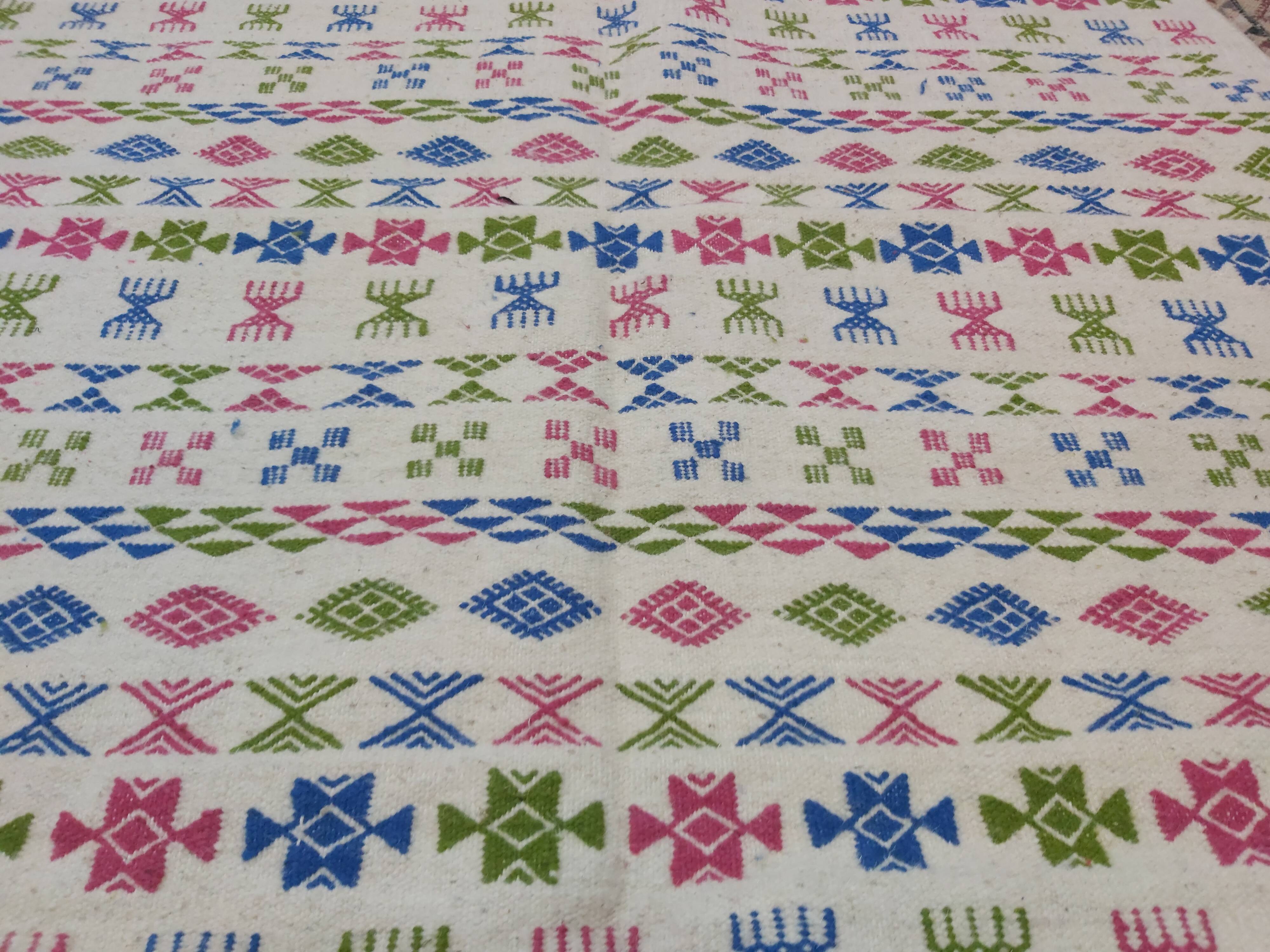 White carpet with Berber motifs pink green and blue