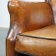 Cognac-colored sheepskin armchair with black piping and decorative nails
