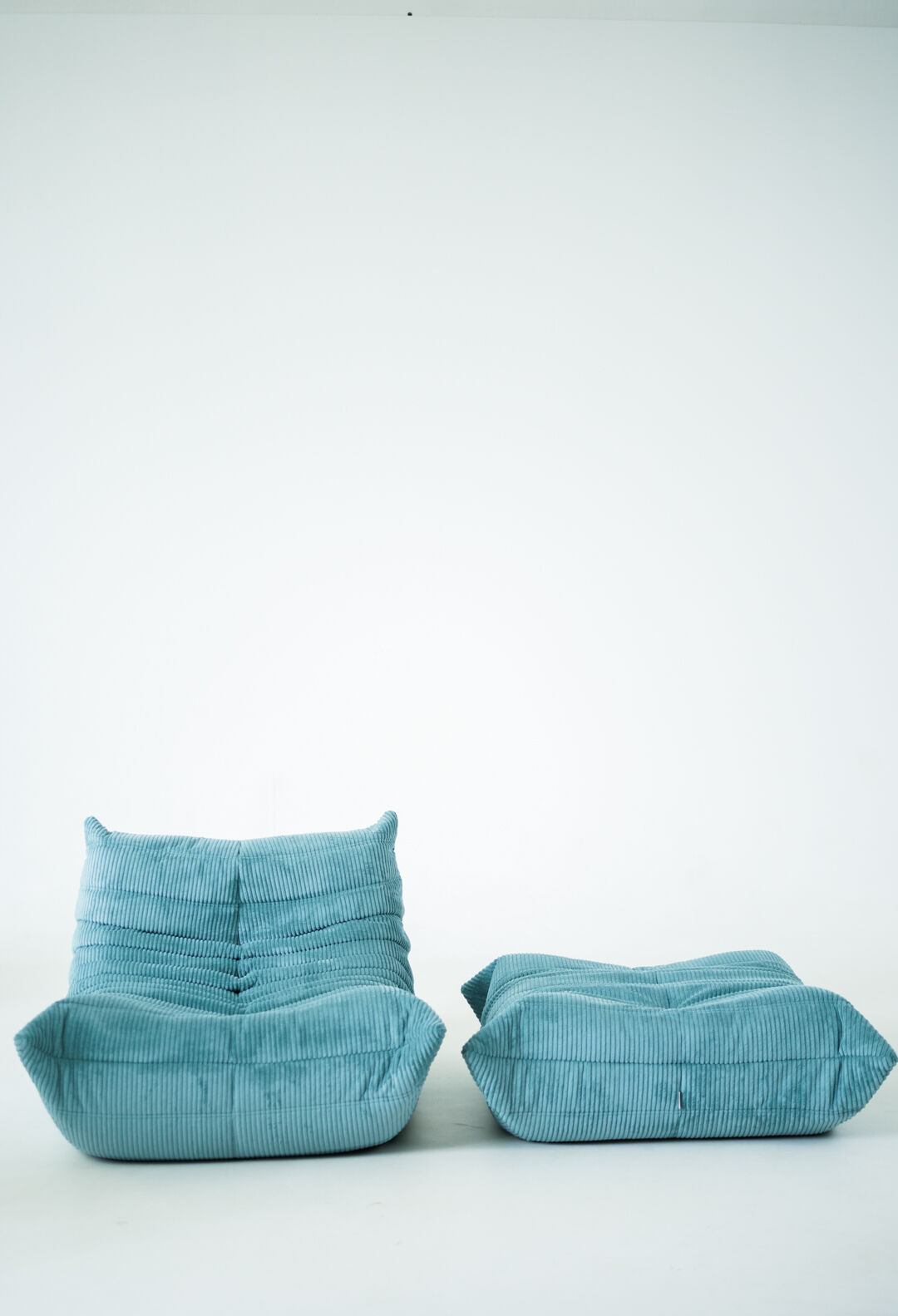 Ensemble de fauteuil et pouf Togo en velours côtelé bleu clair.