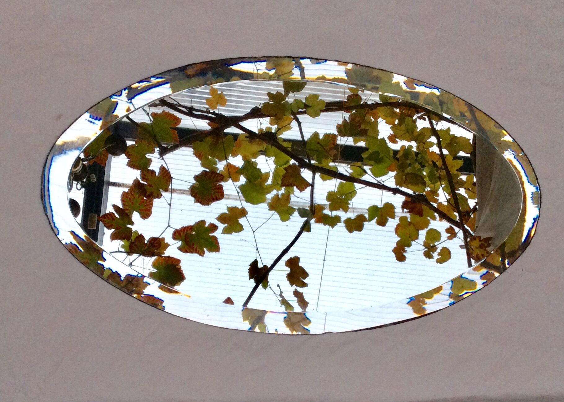 Beveled oval mirror stitched at the edges around the 1930
