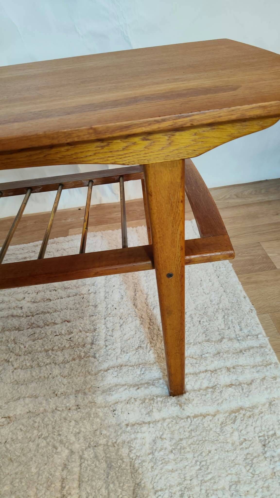 Scandinavian coffee table in teak with a lower shelf and brass bars.