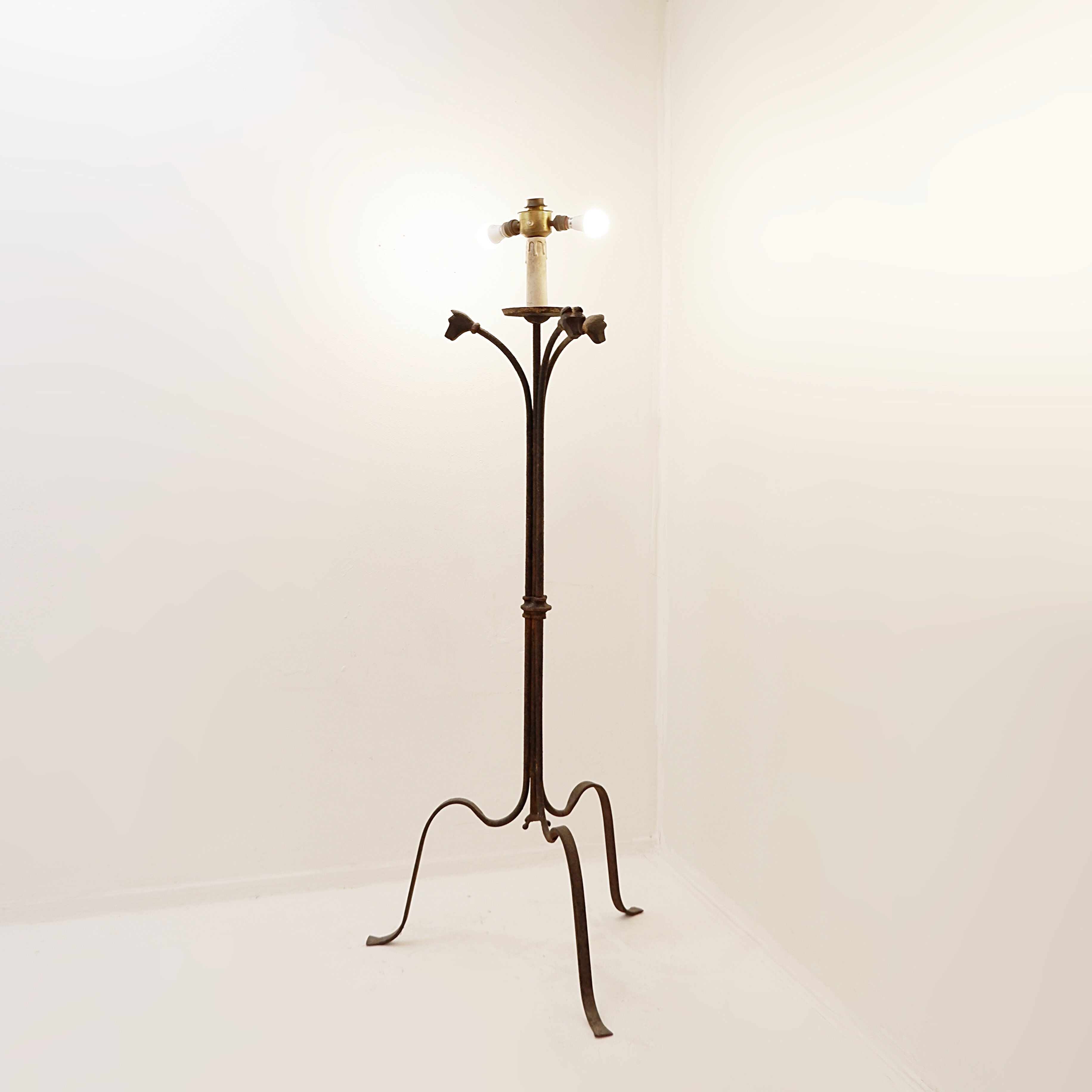 Wrought iron tripod floor lamp decorated with stylized animal heads