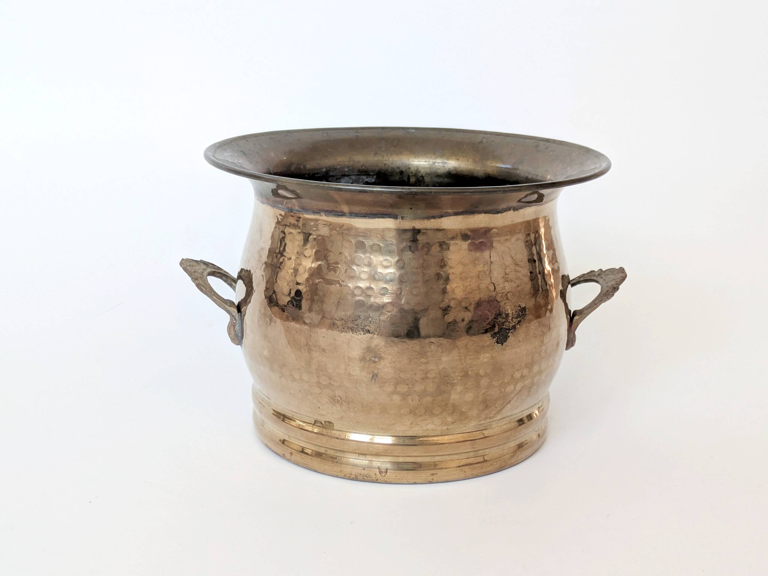 Vintage round cache-pot in hammered brass with decorative handles and patina.