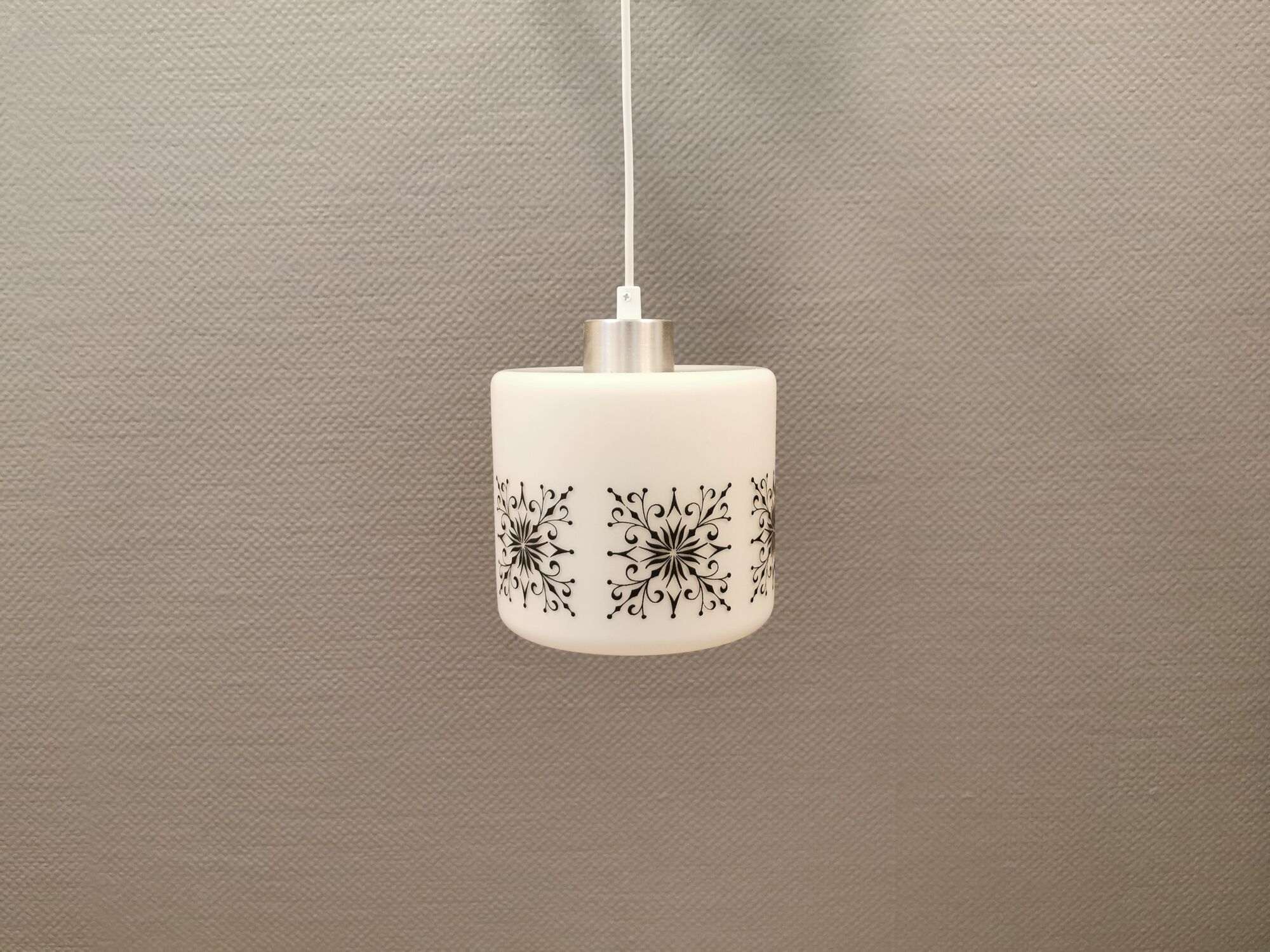 Scandinavian hanging lamp in white glass with inlayed black motifs.