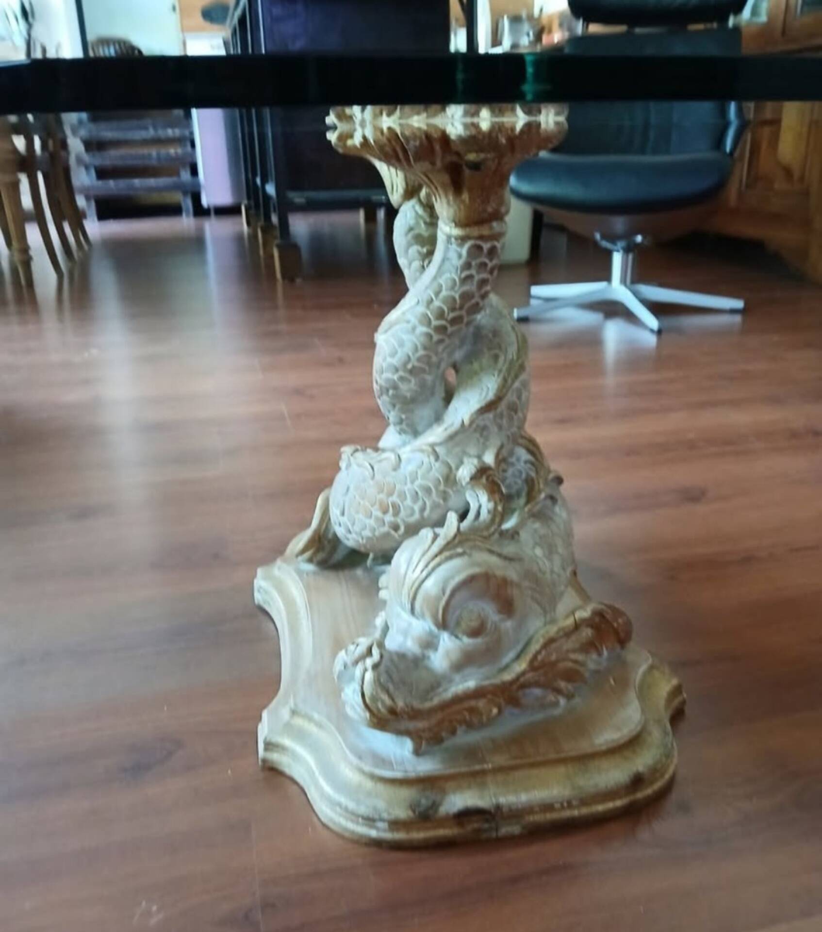Glass table with carved wooden legs featuring intertwined fish.