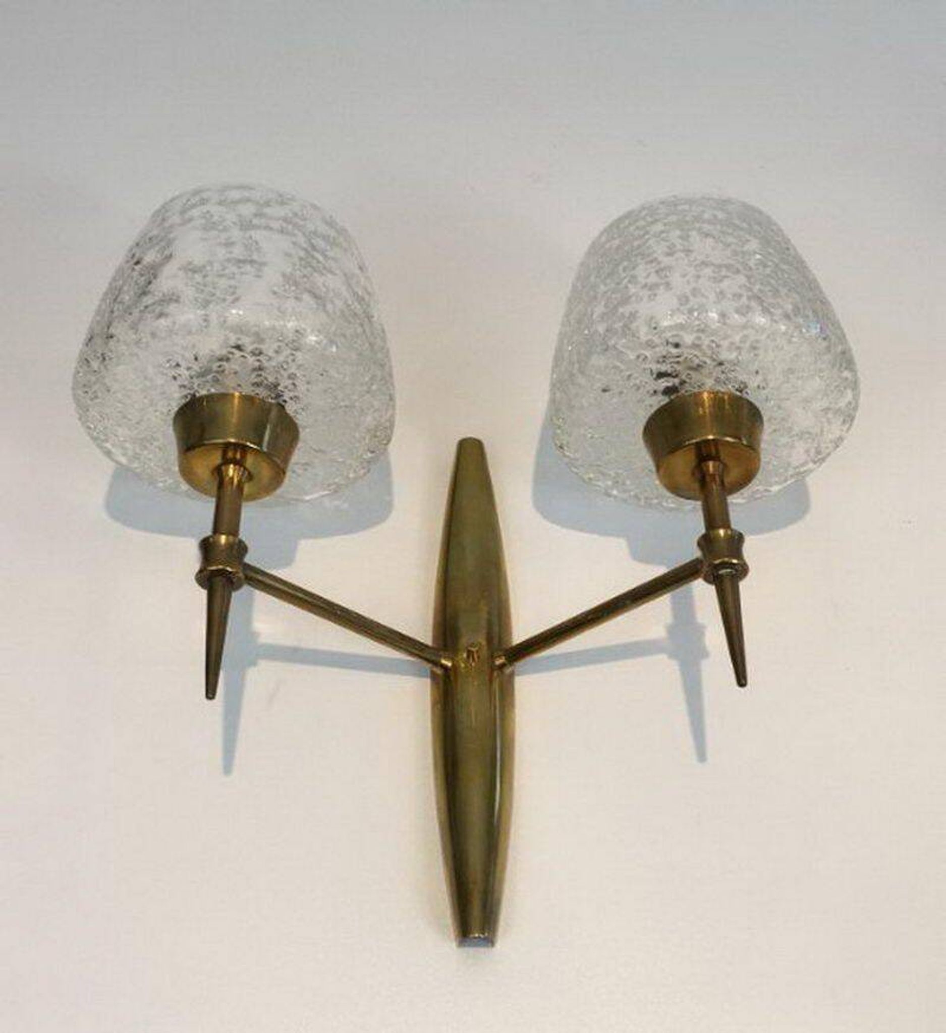Pair of bronze wall sconces with worked glass reflectors. Stilnovo