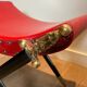 Neoclassical curule stool in red leather, decorated with crossed swords in bronze and metal covered in black leather.