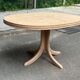 Renovated oval Scandinavian extendable dining table in wood with a central leg.
