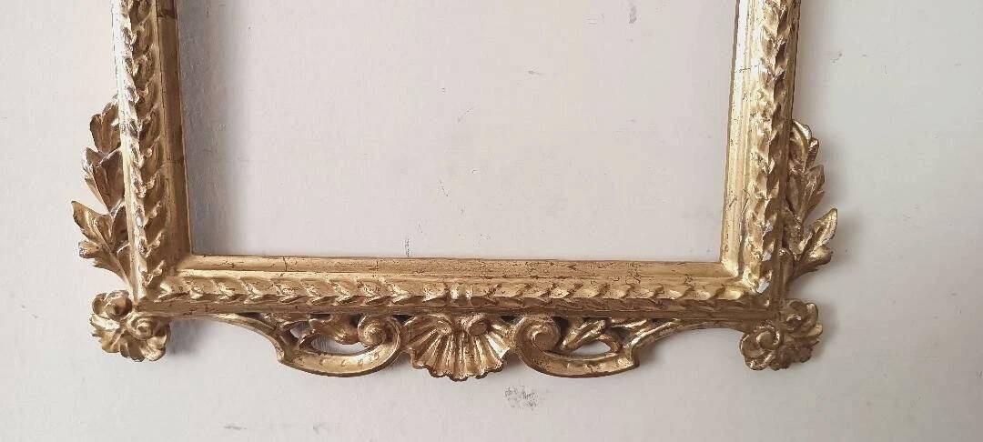Mirror with a carved wooden frame in an antique style in pure gold.