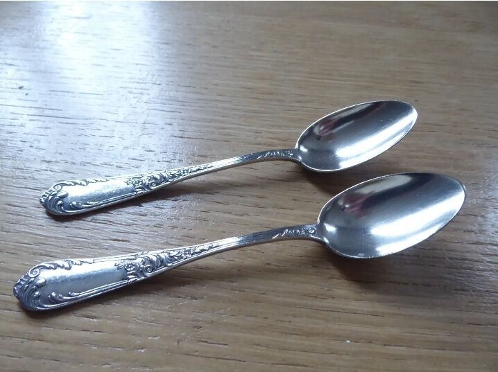 2 small white metal spoons