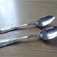 2 small white metal spoons