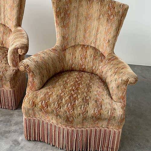 Pair of sculptural Hollywood Regency lounge chairs with original fringed upholstery