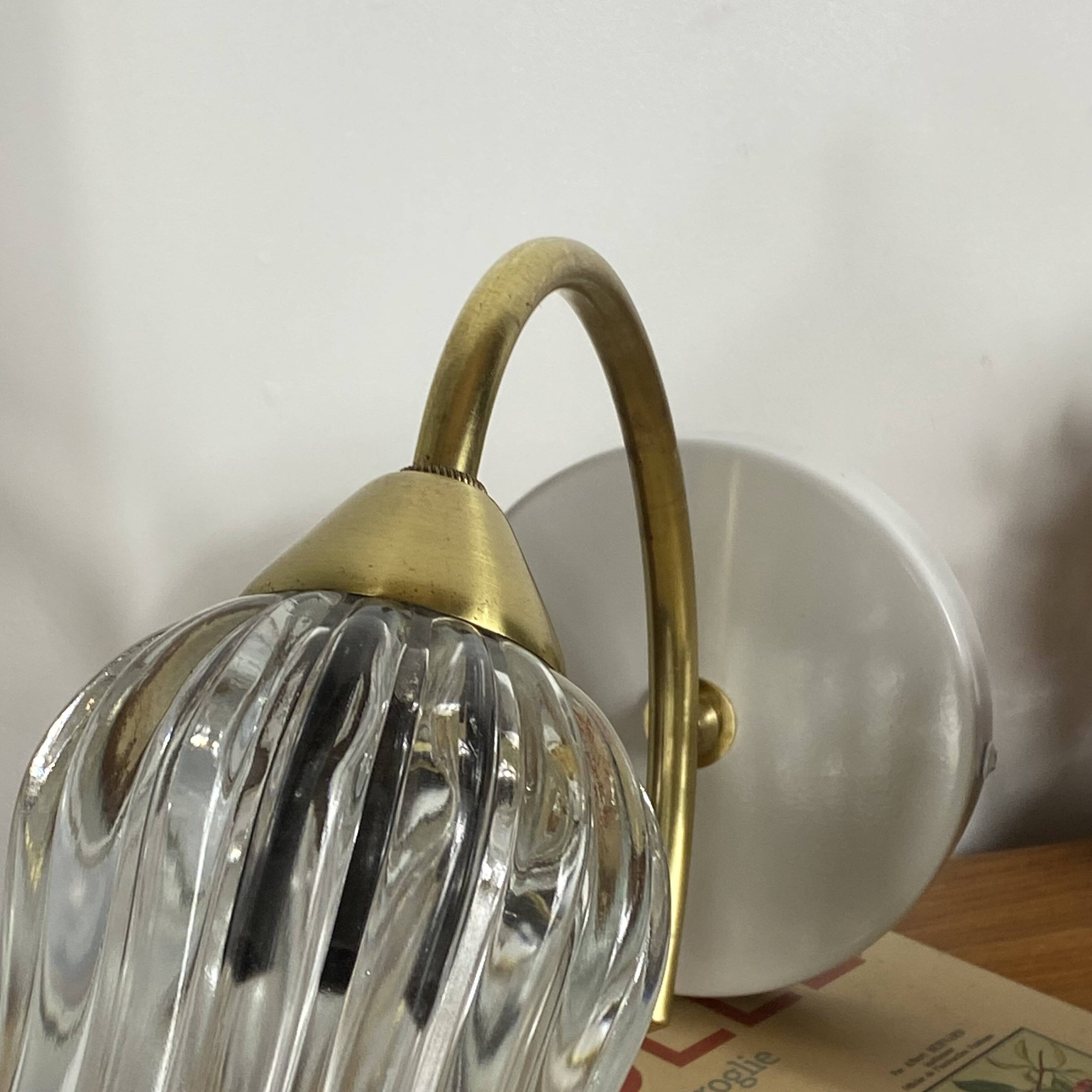 Pair of wall sconces in brass with transparent tulip glass shade.