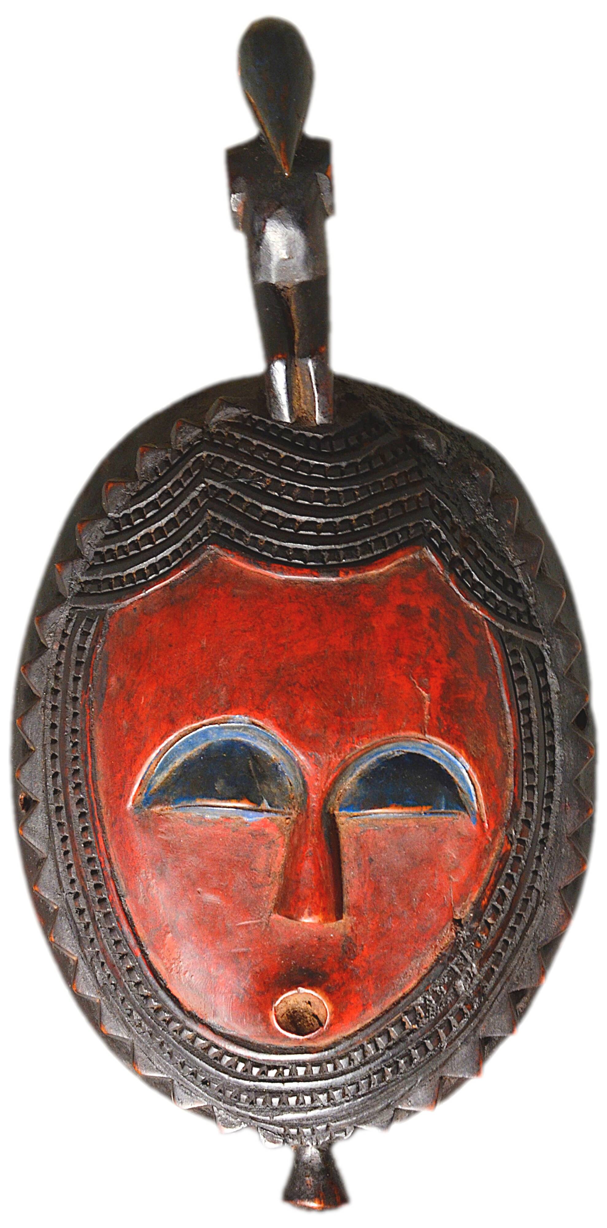 African wooden mask, face topped with a bird.