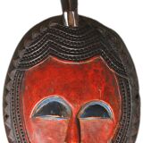 African wooden mask, face topped with a bird.