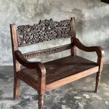 Small antique Indonesian bench in carved teak with plant and floral motifs.