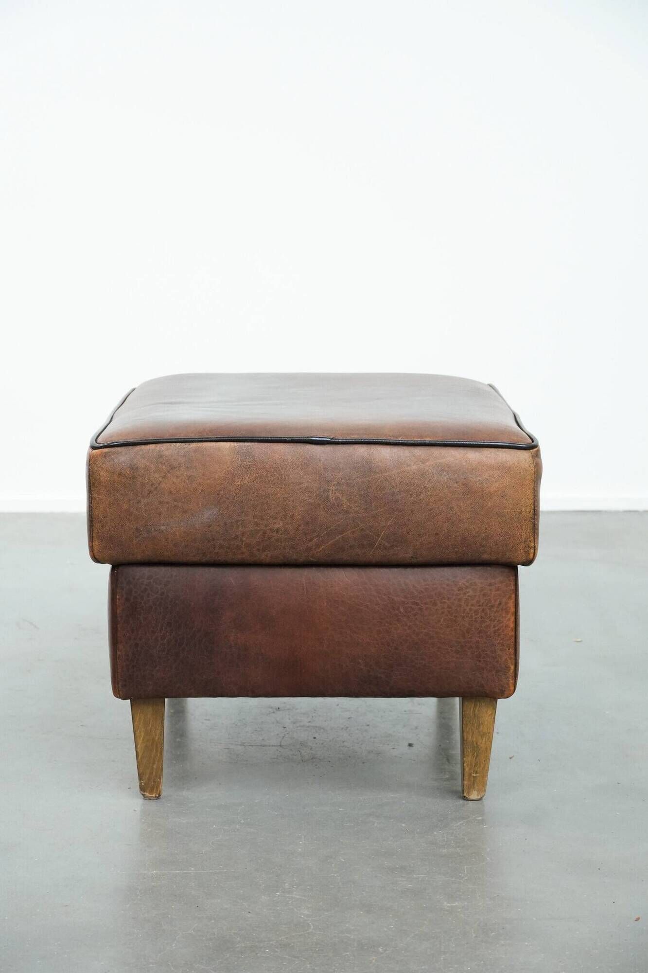 Sturdy vintage sheepskin ottoman in a beautiful large size with black piping