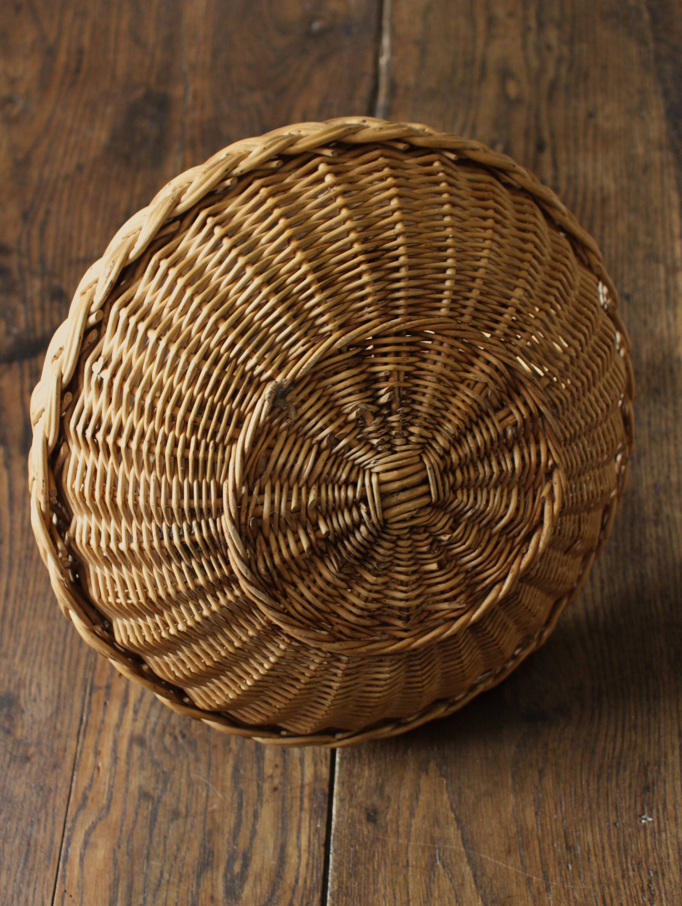 Round wicker basket with a rigid handle.