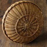 Round wicker basket with a rigid handle.
