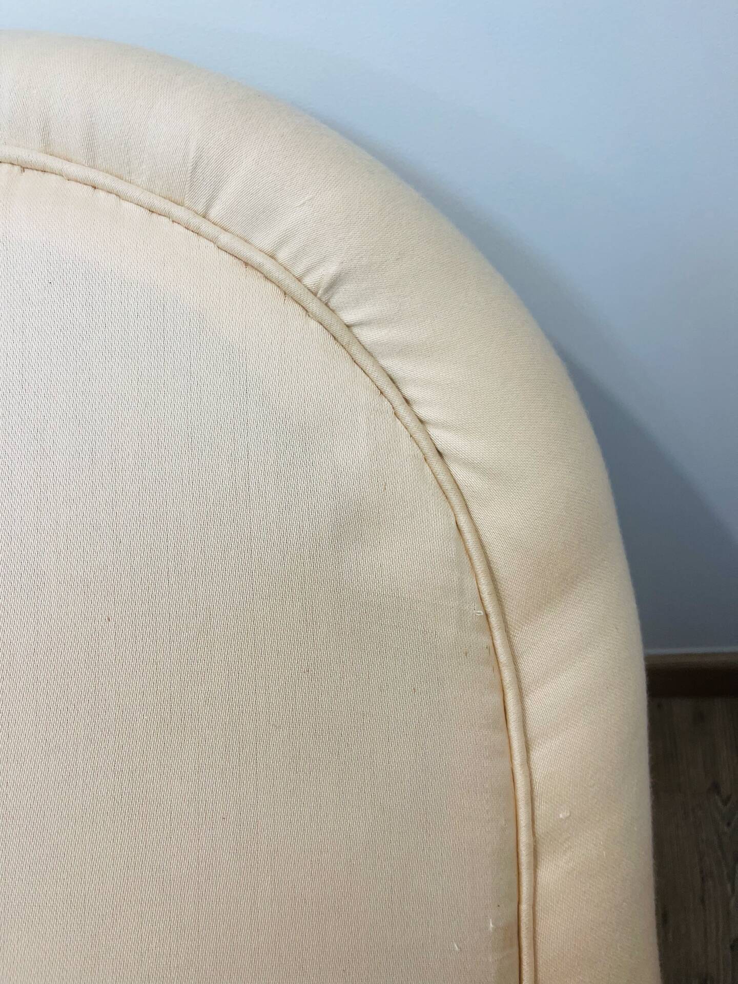 Pale pink upholstered armchair with wooden legs.