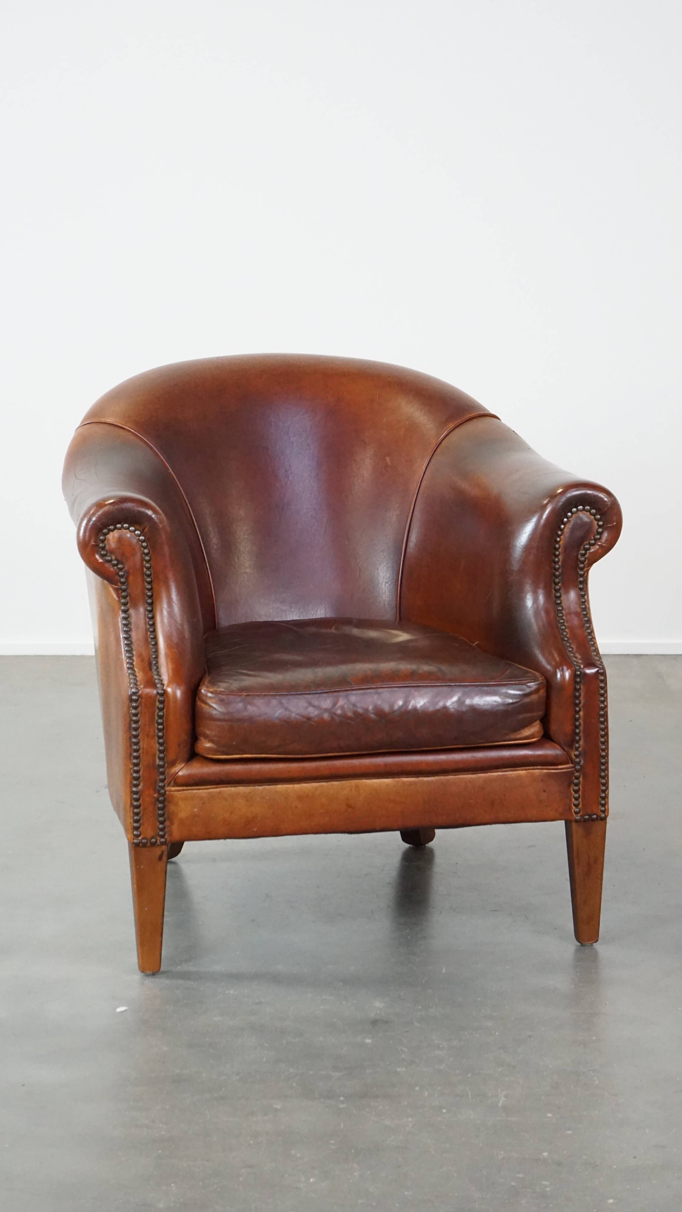 Un fauteuil club robuste mais confortable en cuir de mouton et fini avec des clous décoratifs