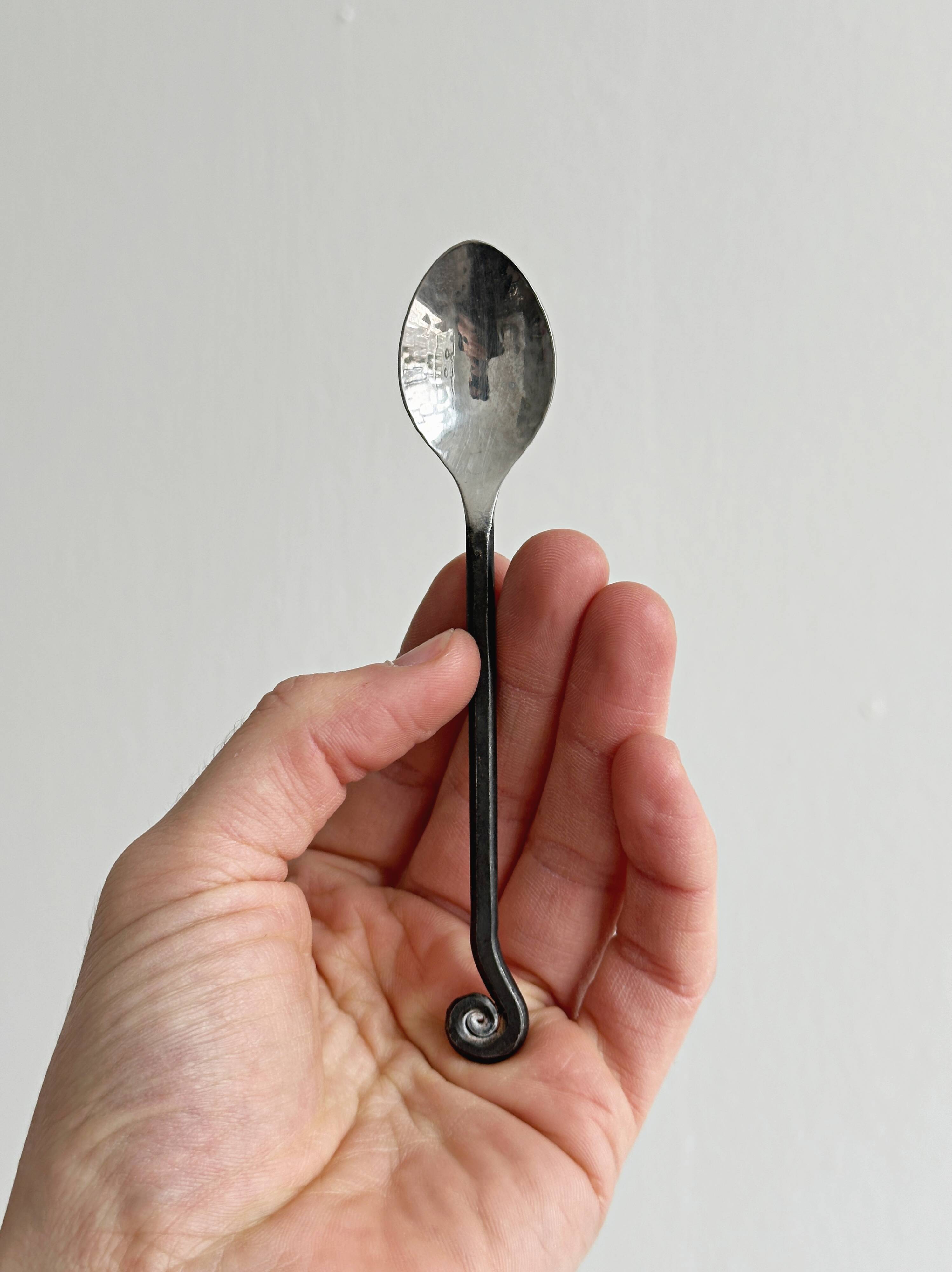 Two small hammered metal teaspoons with a snail pattern.