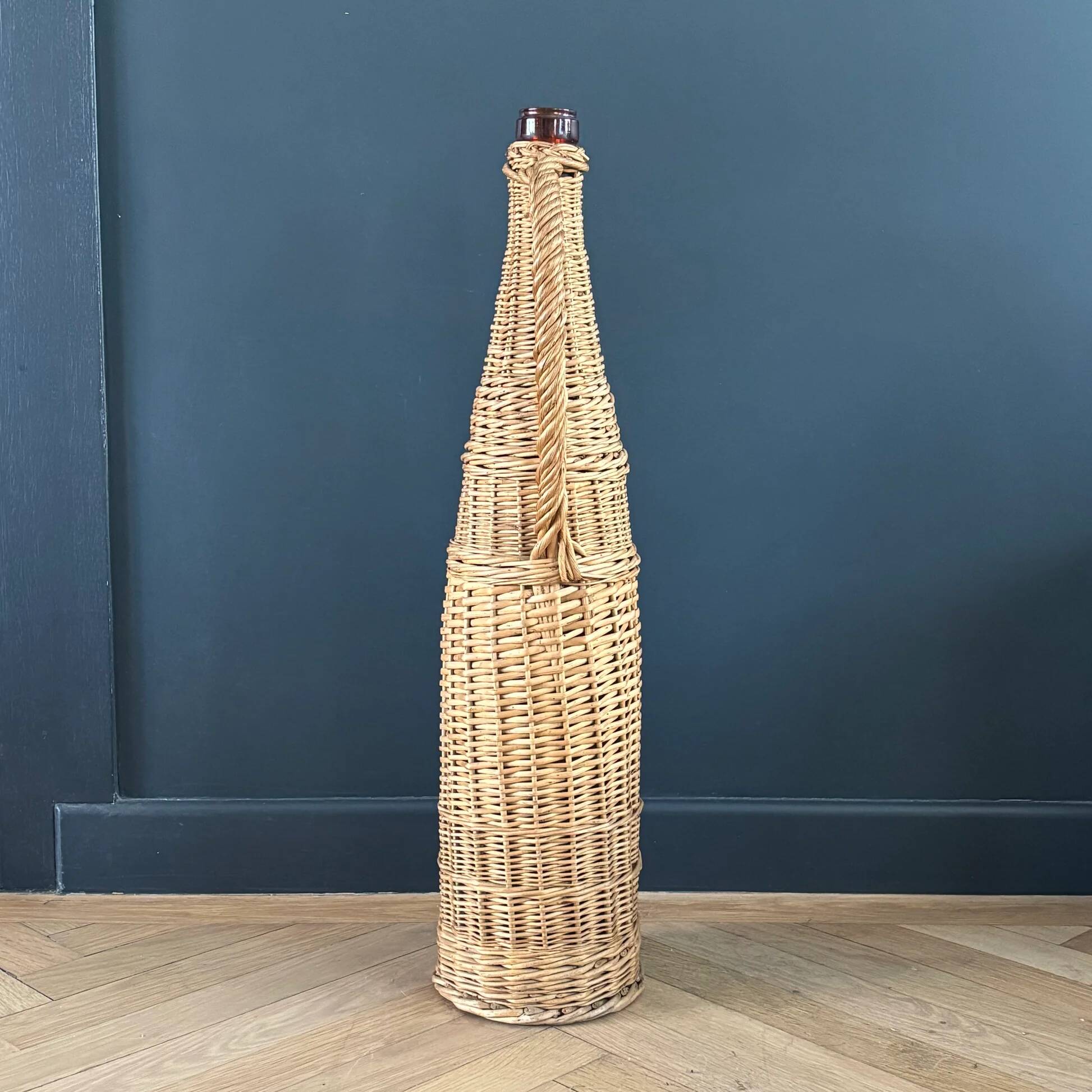 Bouteille en verre ambré dans son panier à poignée en osier
