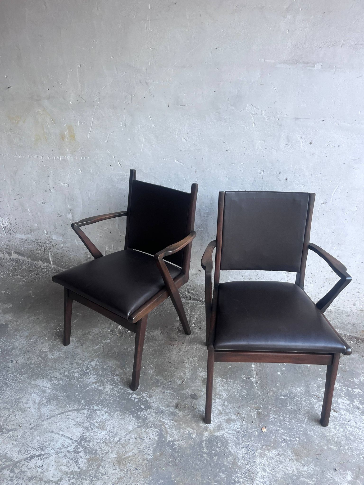 Pair of sculptural mid-century armchairs in dark wood and brown upholstery.