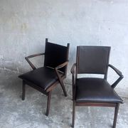 Pair of sculptural mid-century armchairs in dark wood and brown upholstery.