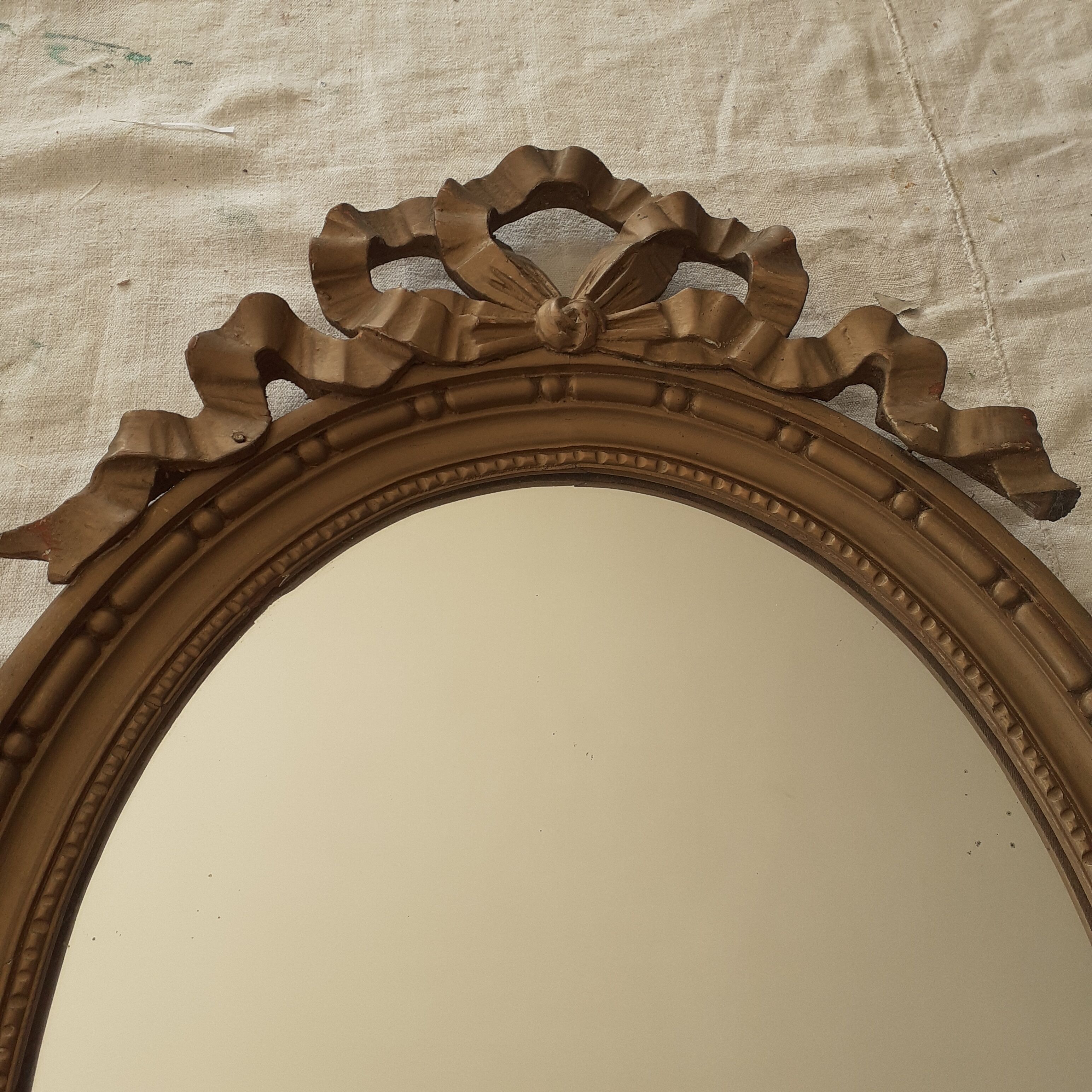 Old oval wooden mirror, surmounted by a knot