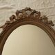 Old oval wooden mirror, surmounted by a knot