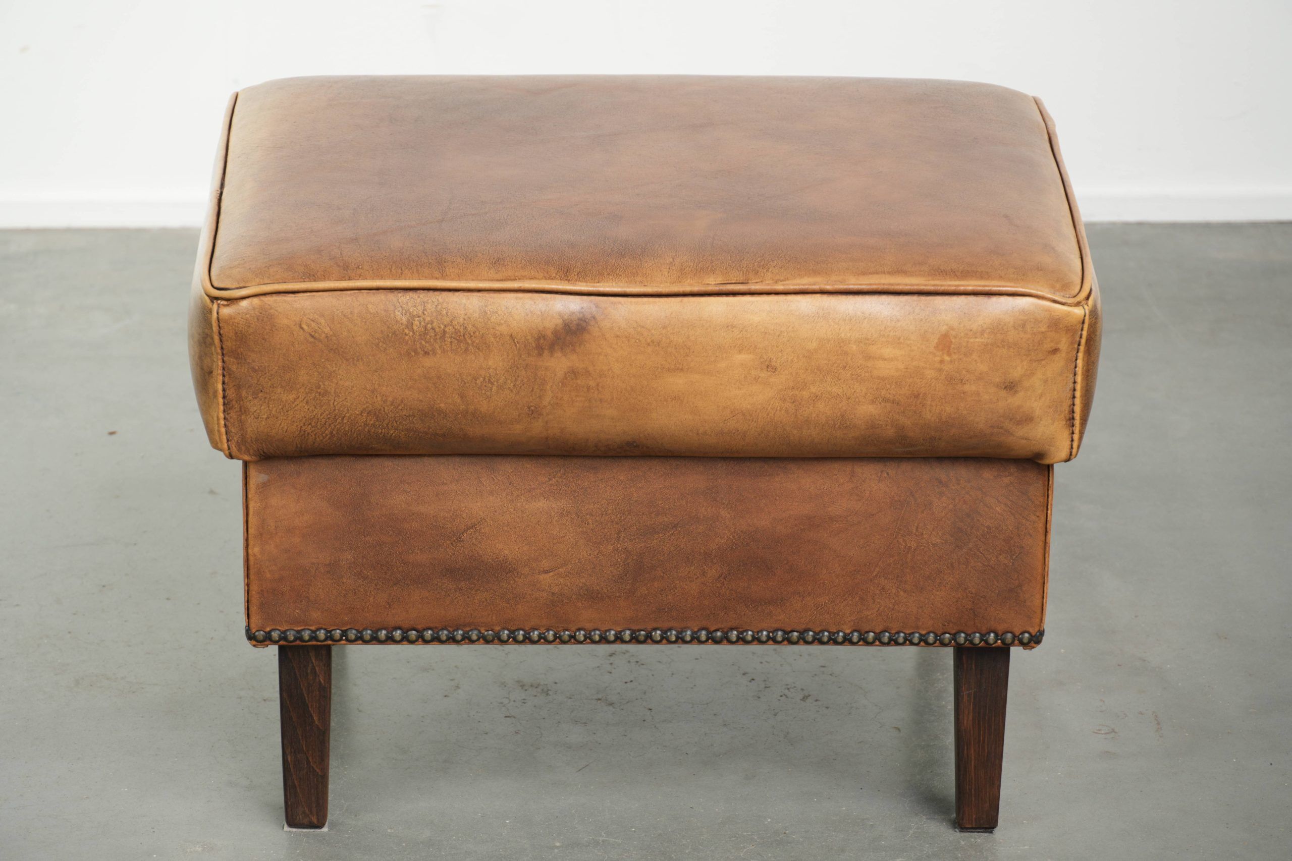 Cowhide ottoman with a beautiful patina finished with decorative nails