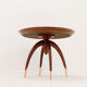 Round Art Deco side table in wood with curved legs and brass feet.