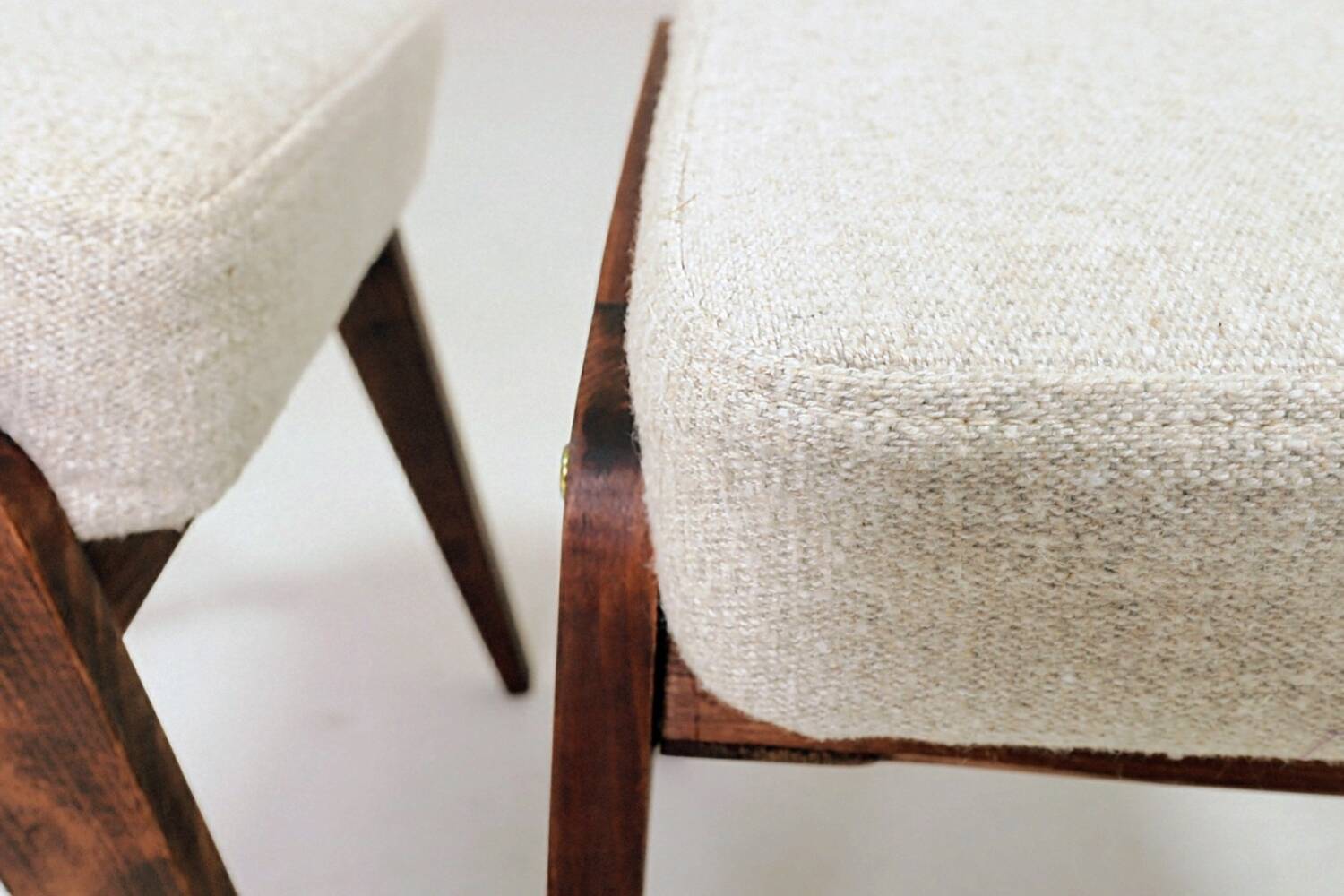 Pair of wooden stools with beige fabric.