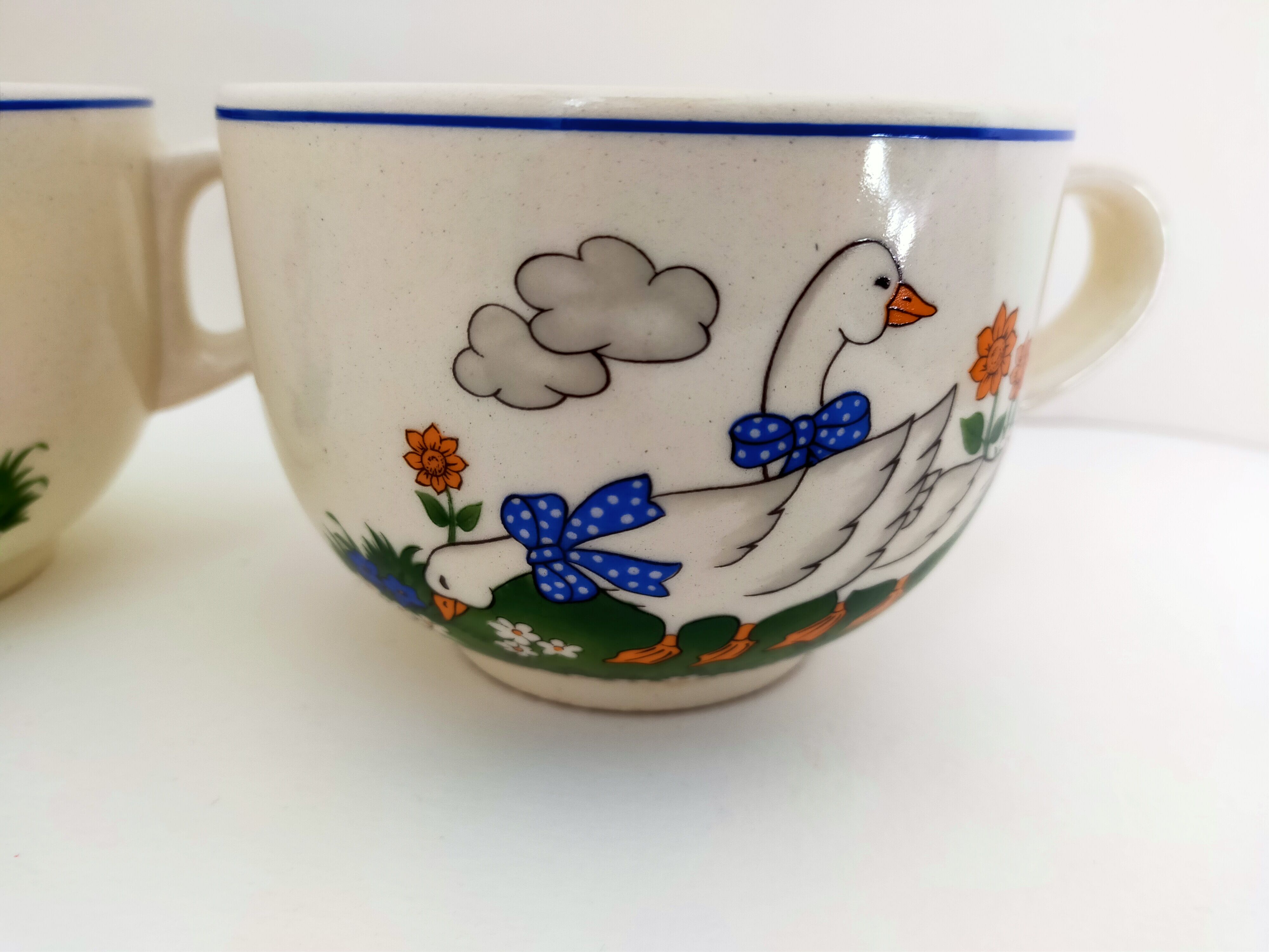 Paire de bols blancs avec anse vintage faïence art déco décor animalier:oies aux rubans bleus