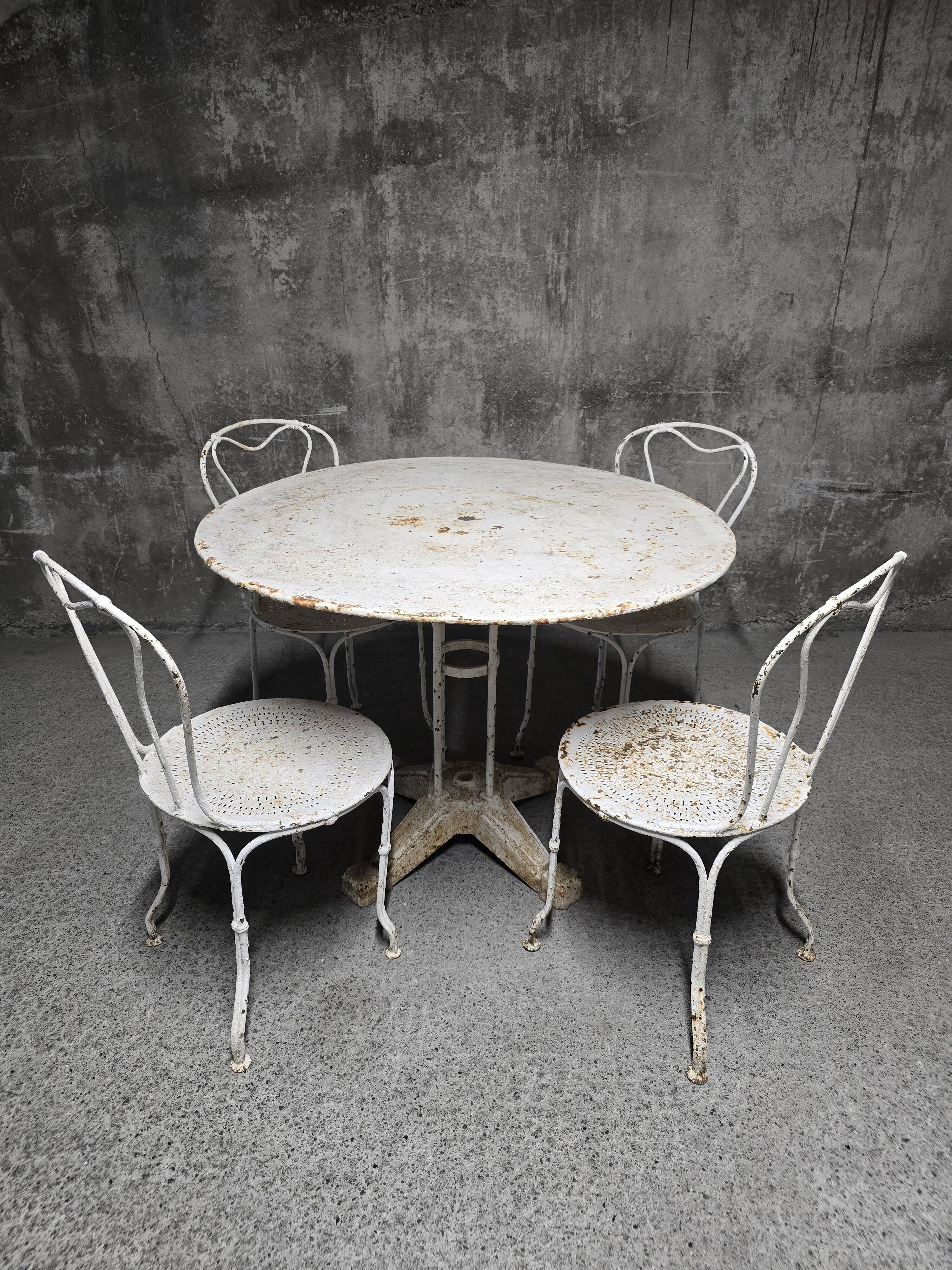 Antique painted wrought iron garden furniture, round table and four chairs.