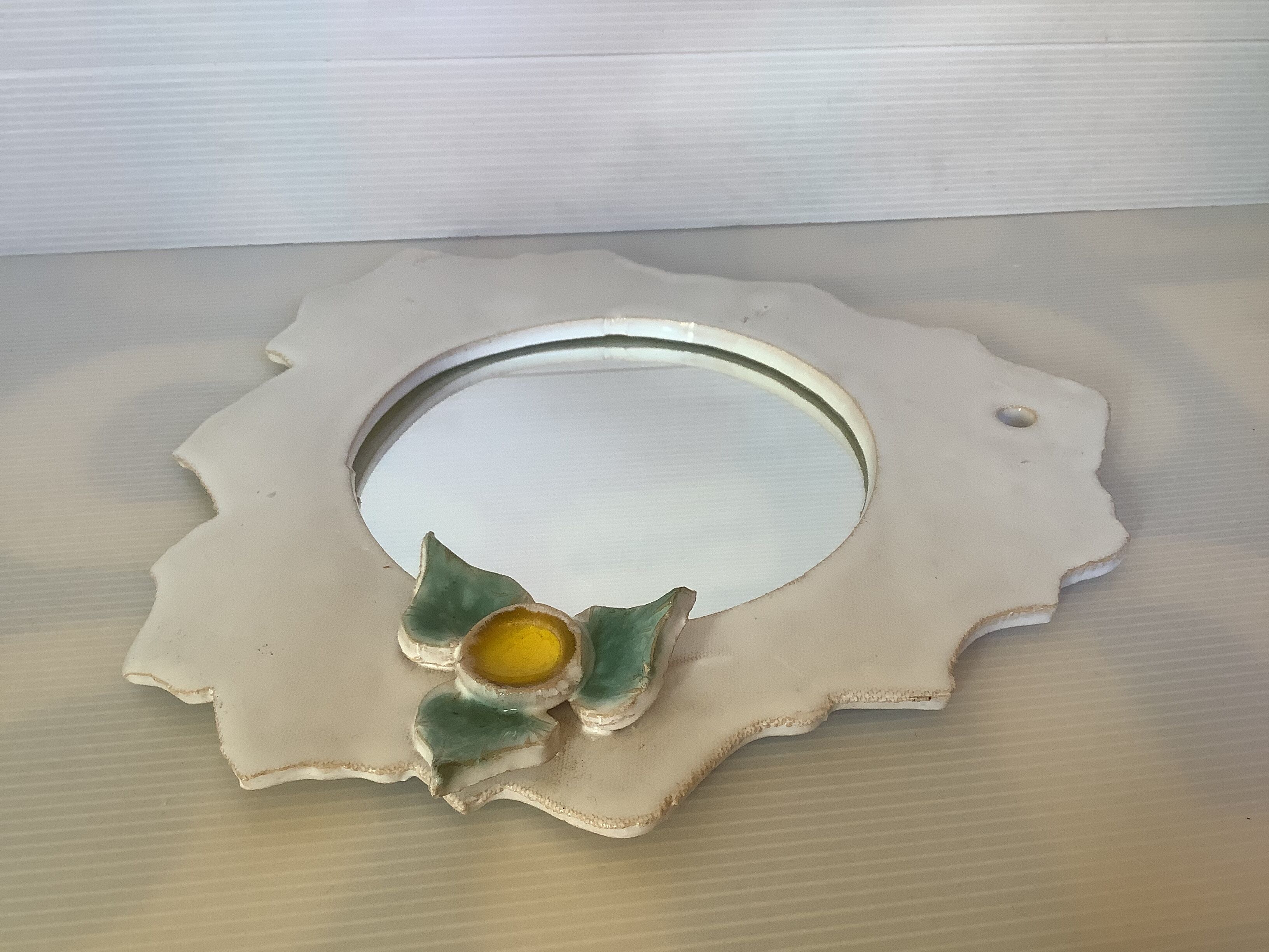 Ceramic mirror with serrated edge and a flower