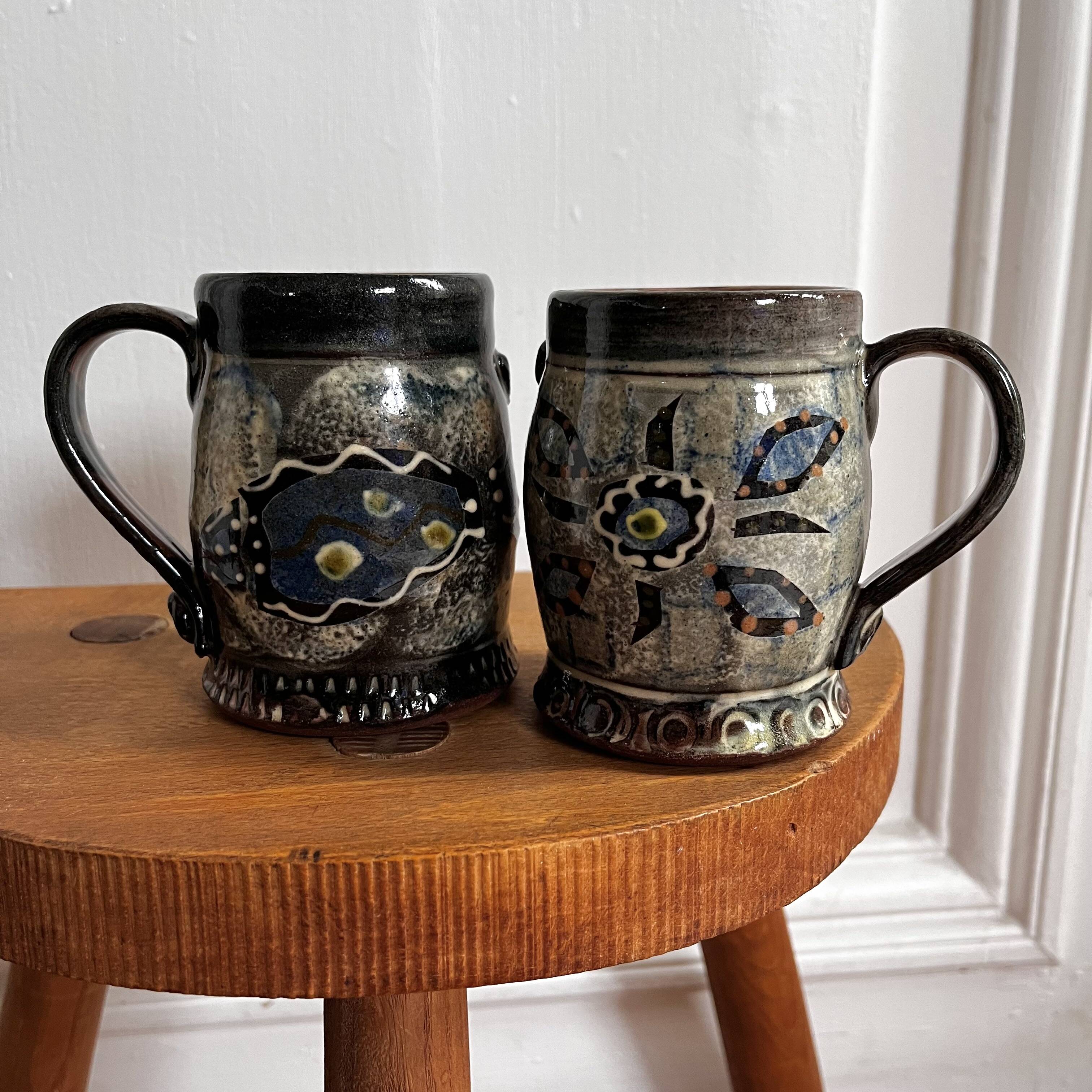 Vintage terracotta mugs with glazed designs and flower/fish motifs