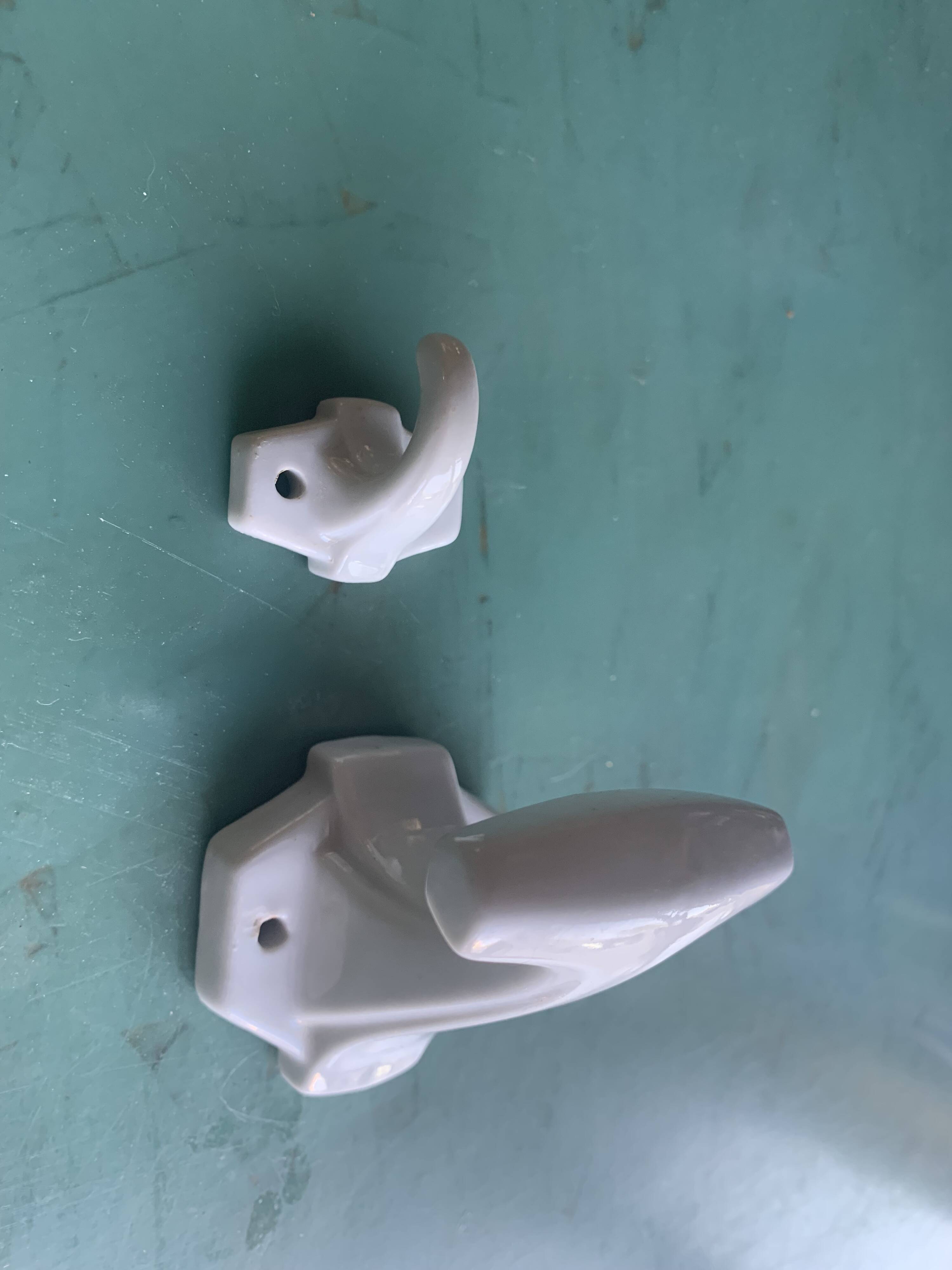 Two white porcelain coat hooks, one small and one larger, old