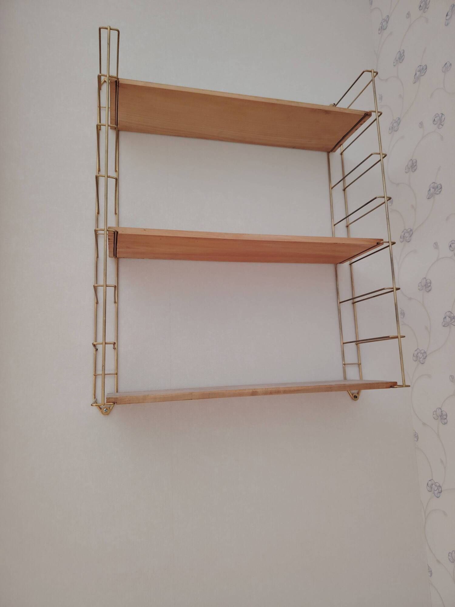 Vintage modular wall shelf in golden steel wire and wood from the 1950s.