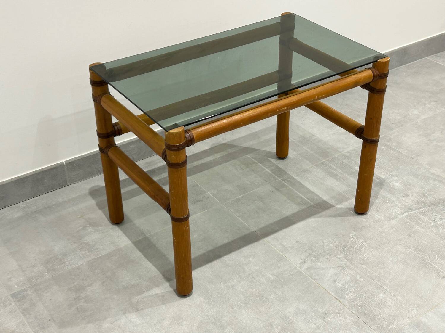 Blonde wood coffee table with smoked glass and leather bindings.