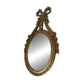 Oval convex witch mirror with golden ribbon mouldings.