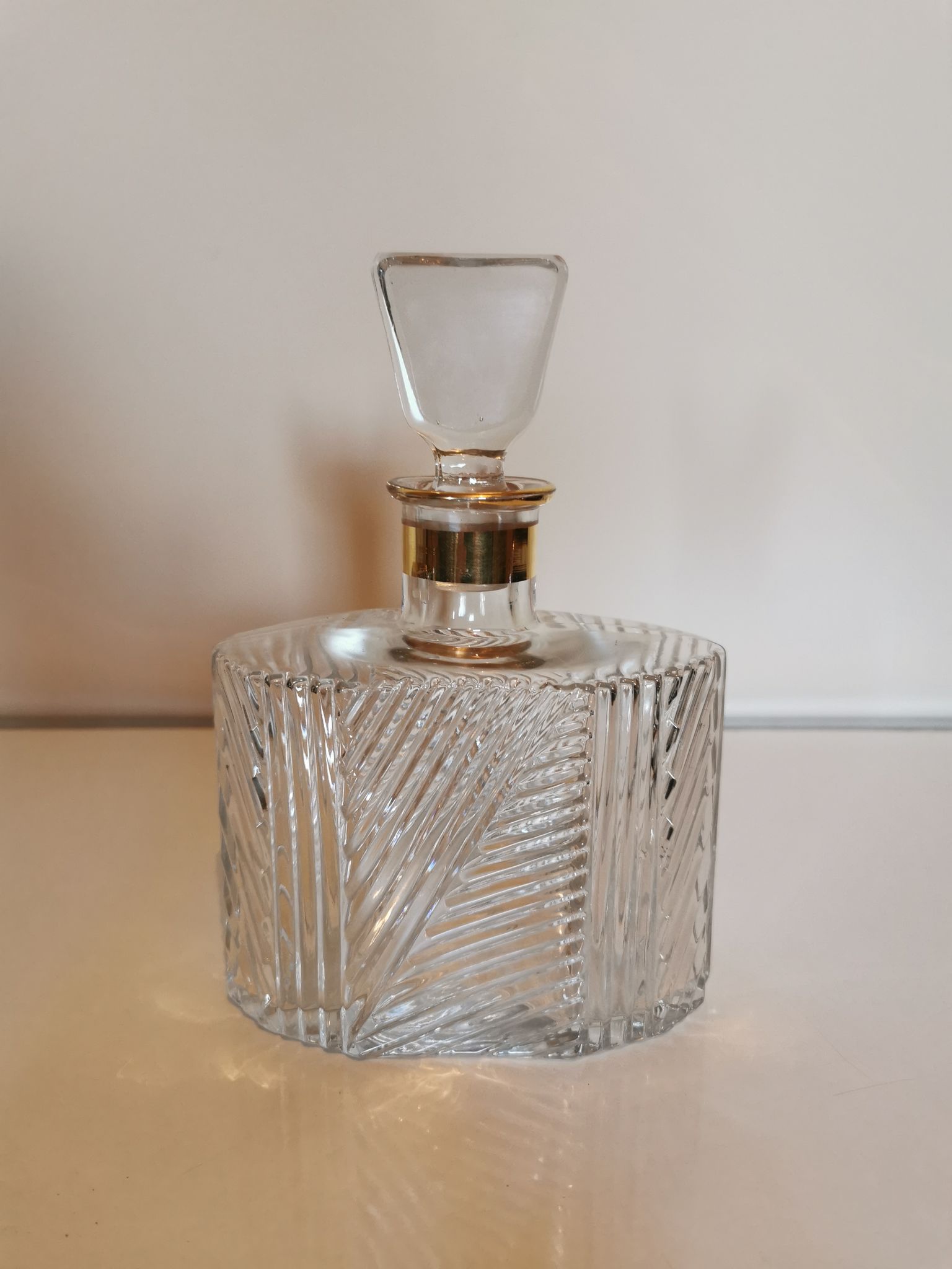 Cut glass carafe with a gold band on the neck.