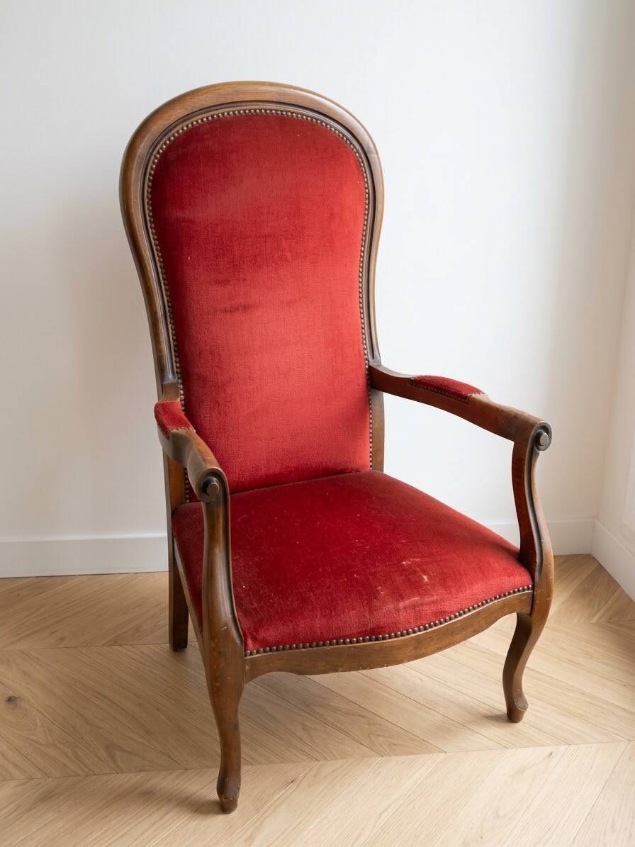 Antique armchair in carved wood and red fabric.