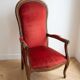 Antique armchair in carved wood and red fabric.
