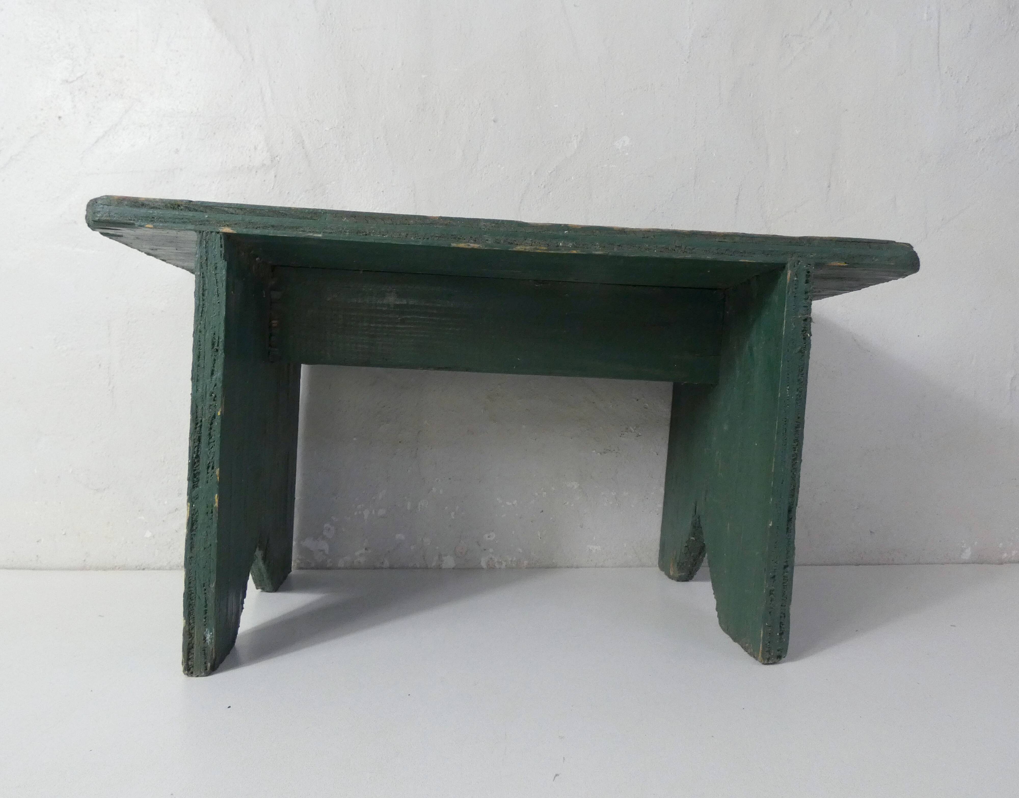 Old small wooden bench with green foot