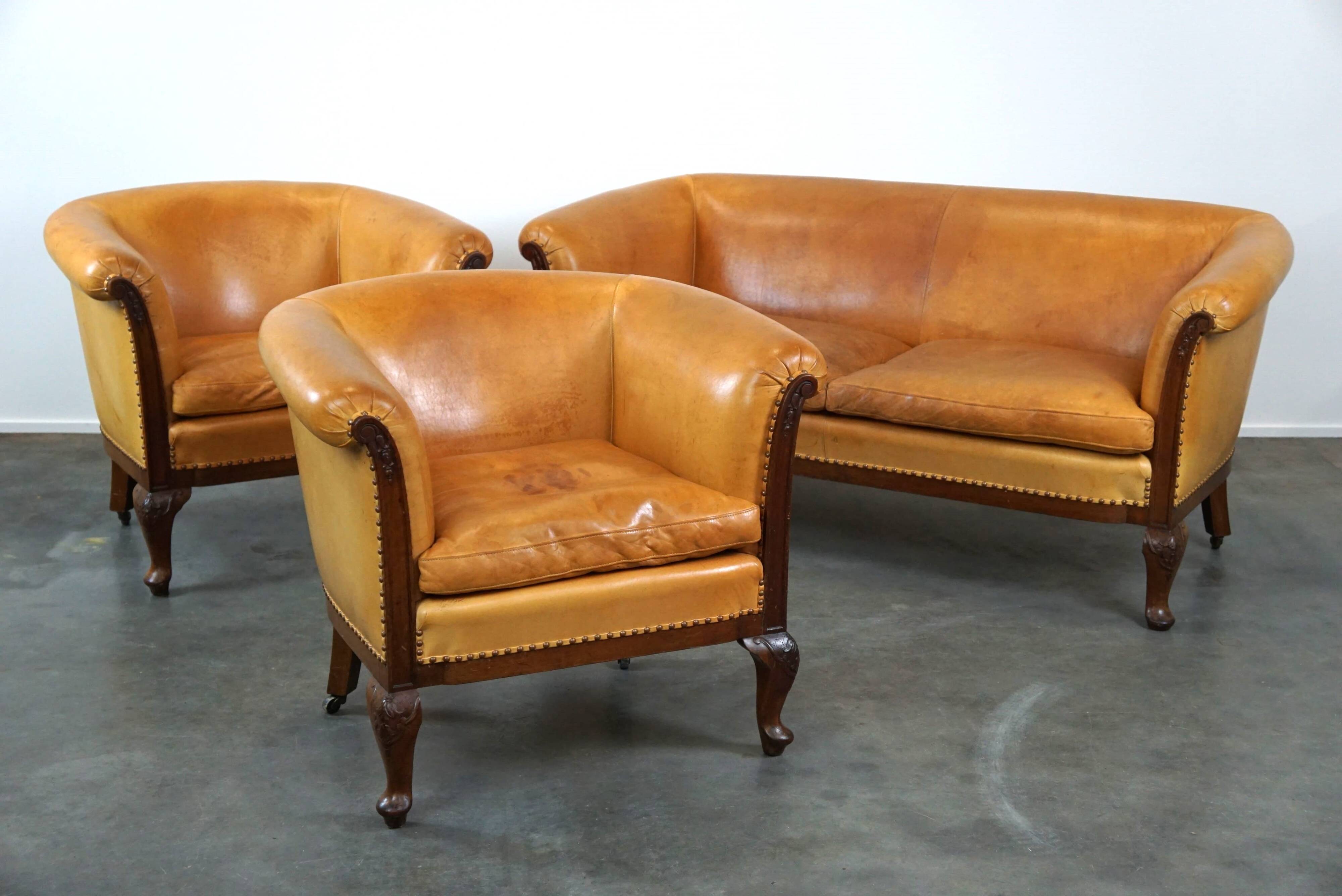 Unique old set of 2 club armchairs and a couch in cognac-colored leather with wheels