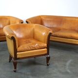 Ensemble ancien unique composé de 2 fauteuils club et d'un canapé en cuir couleur cognac à roulettes
