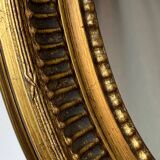 Oval-shaped wooden mirror in gold color